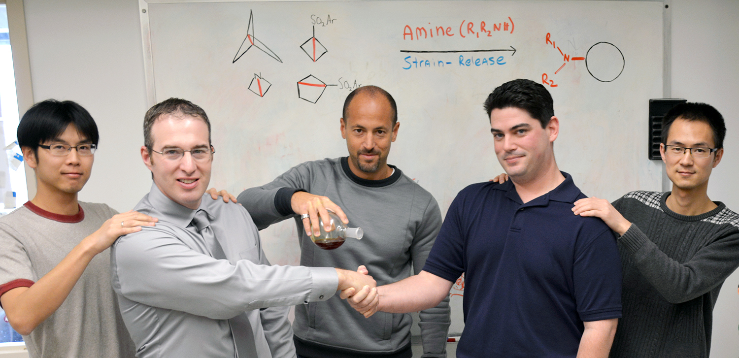 Chemists from The Scripps Research Institute illustrate their powerful new technique to make and modify medicines, published recently in the journal Science. Professor Phil Baran (center) holds a flask representing amines to cleave strained C–C bonds, which are depicted by a tug-of-war between co-first authors Ryan Gianatassio (left center) and Justin Lopchuk (right center) with co-authors Chung-Mao Pan (left) and Jie Wang.