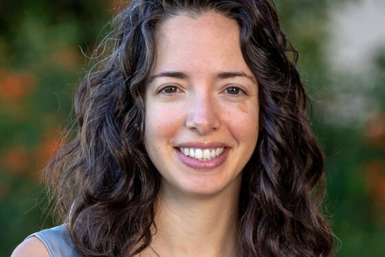 Professional headshot of Julia Moore Vogel with greenery in the background.