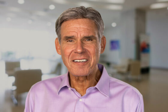 Professional headshot of Eric Topol, Scripps Research Executive Vice President and Founder of SRTI, in a light pink shirt with a modern office background.