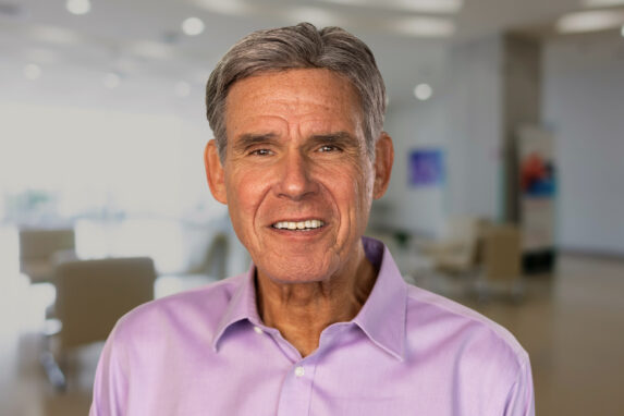 Professional headshot of Eric Topol, Scripps Research Executive Vice President and Founder of SRTI, in a light pink shirt with a modern office background.