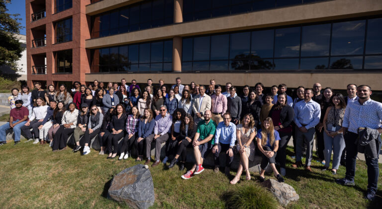 Large group photo of the Scripps Research Translational Institute team gathered outdoors in front of a brick research building.