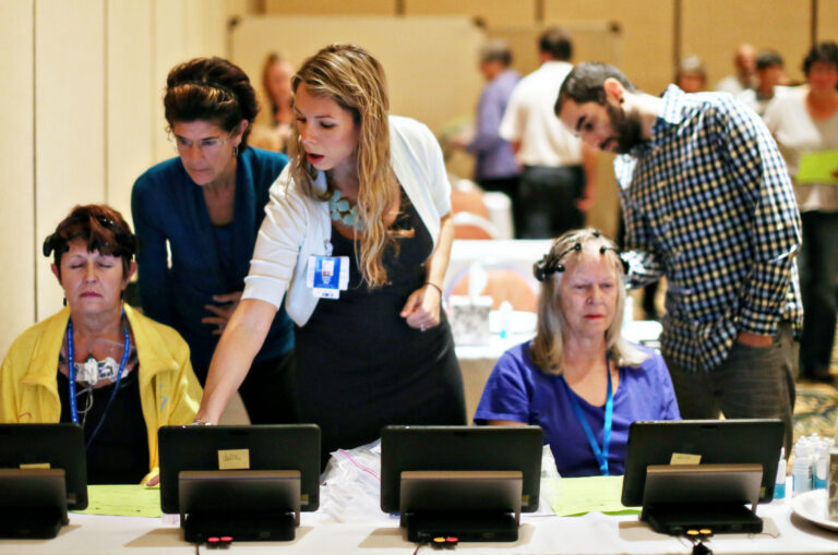 SRTI research navigation staff assisting study participants using tablets at a clinical research event.