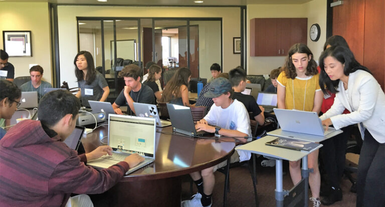 High school students working on laptops during the Scripps Research Computational Biology Research Camp with instructor assistance.