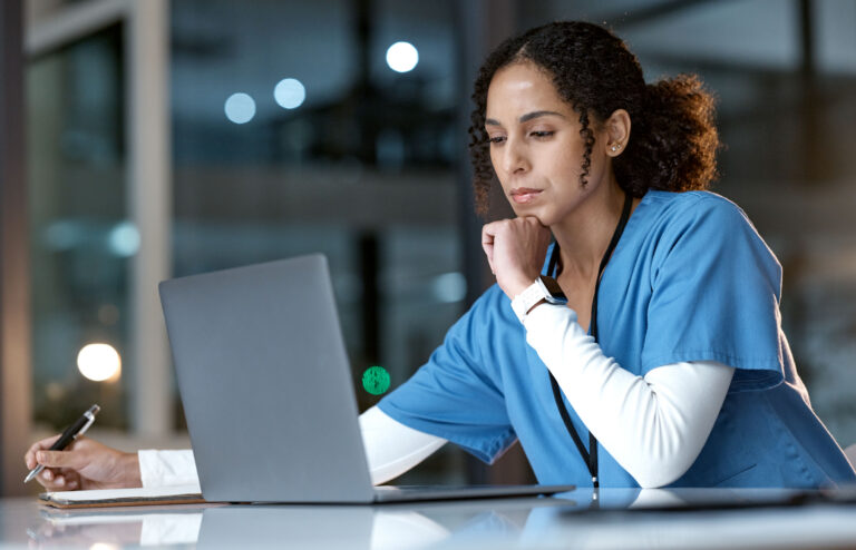 Healthcare professional in blue scrubs studying at a laptop, representing online CME and CNE continuing education modules.