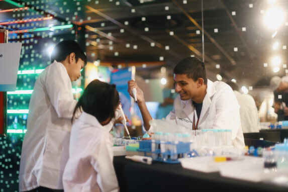 Scripps Research scientists in white lab coats pipetting samples during a hands-on science outreach event