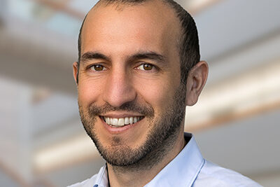 Professional headshot of Ali Torkamani, Scripps Research Translational Institute faculty member, with a bright indoor background.