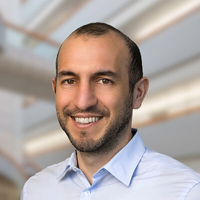 Professional headshot of Ali Torkamani, Scripps Research Translational Institute faculty member, with a bright indoor background.