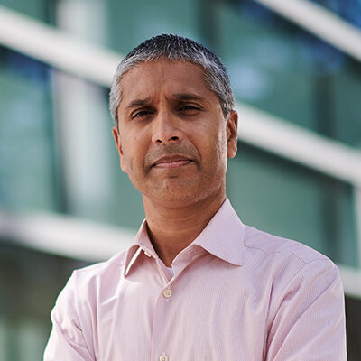 Professional headshot of Arnab Chatterjee, Scripps Research faculty and SRTI Executive Committee member, outdoors in front of a glass building.