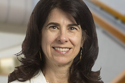 Professional headshot of Athena Philis-Tsimikas, Scripps Research Translational Institute faculty, with staircase background.