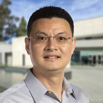 Professional headshot of Chunlei Wu, Scripps Research Translational Institute faculty, with Scripps campus buildings in the background.