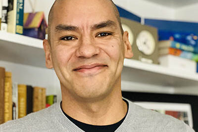 Professional headshot of Ed Ramos, Scripps Research Translational Institute staff member, in front of a bookshelf.