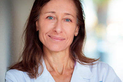 Professional headshot of Laura Nicholson, MD, Scripps Research physician-scientist, wearing a white clinical lab coat.