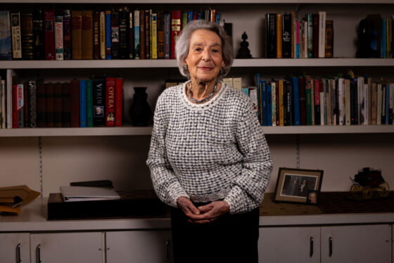 Scripps Research donor standing in front of a bookshelf filled with books, smiling at the camera