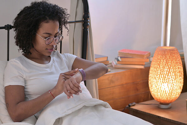 Woman sitting in bed looking at an activity tracker.