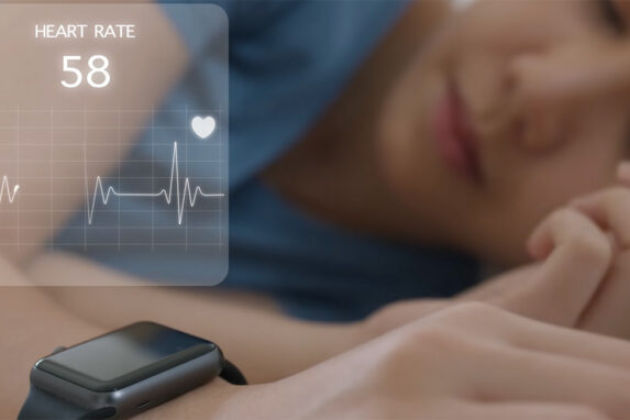 Woman sleeping with smartwatch on her wrist and heart rate data displaying on an image overlay.